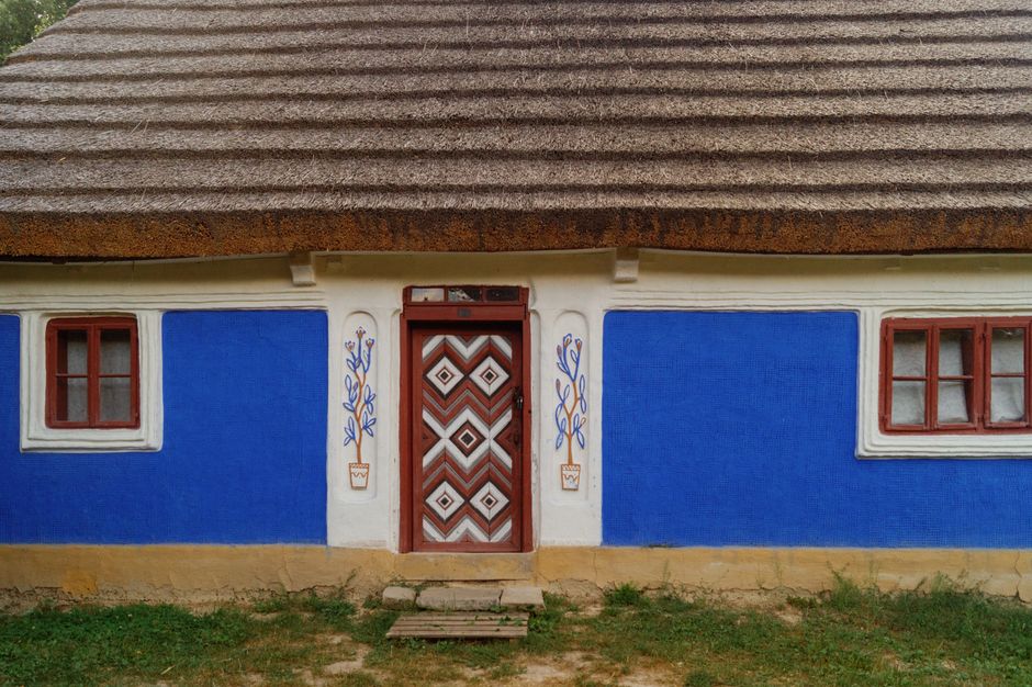Small hut with painted blue walls and a thatched roof.